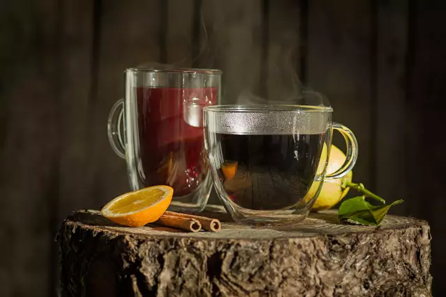 Two glasses of mulled wine surrounded by a decoration of spices, lemon and orange slices.